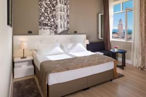 ein Schlafzimmer mit einem großen Bett und einem Fenster in der Unterkunft Cornaro Hotel in Split