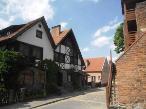 an old white and black house with a brick building at Hotelik in Chełmno