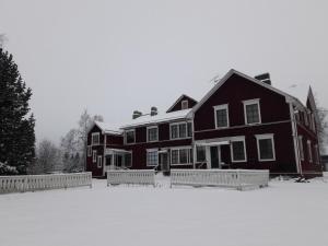 Une grande maison noire avec de la neige au sol dans l'établissement Suvannonrannan Majoitukset, à Kauhajoki