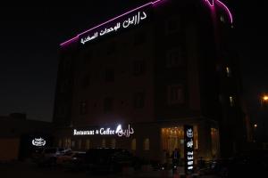 a building with a sign on the side of it at night at Darin Furnished Apartments in Al Bukayriyah