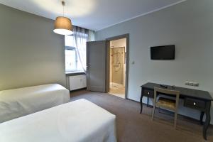 ein Hotelzimmer mit einem Bett, einem Schreibtisch und einem TV in der Unterkunft Avalis Apartamenty in Posen