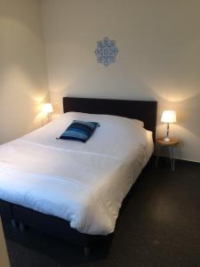 ein großes weißes Bett in einem Zimmer mit zwei Lampen in der Unterkunft Vrije Vlinders in IJzendijke