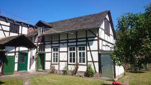 una antigua casa blanca y negra con puertas verdes en Ferienwohnung Weseraue, en Holzminden