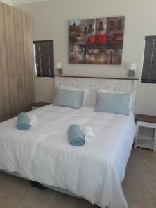 ein Schlafzimmer mit einem großen weißen Bett mit Handtüchern darauf in der Unterkunft Cottage@Somerset in Somerset West