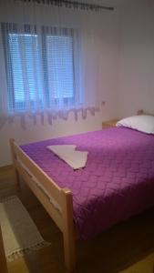 a bed with a purple comforter in a bedroom at Apartman Dolac in Karlobag
