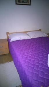 a purple comforter on a bed in a bedroom at Apartman Dolac in Karlobag