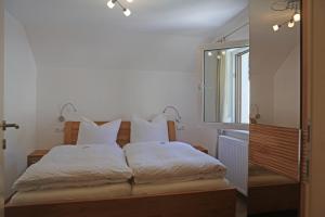 a bedroom with a bed with white sheets and a mirror at Ferienwohnungen Hager in Gosau