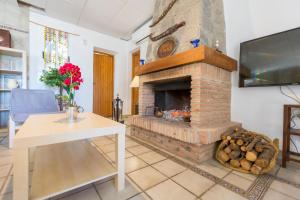 a living room with a brick fireplace with a table and a tv at Casita Cerrillo en Villa de Nijar con piscina in Níjar