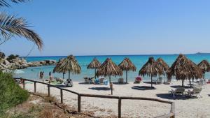 una spiaggia con alcuni ombrelloni di paglia e l'oceano di Appartamento Simius a Villasimius
