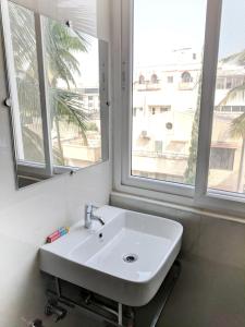 a white sink in a bathroom with two windows at Clyford Suites in Bengaluru +93 photos