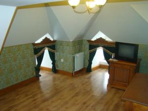 a living room with a tv and a wooden floor at Zámecké ubytování U dobré hraběnky in Kunín