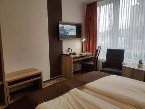 um quarto de hotel com uma cama, uma secretária e uma televisão em Park Hotel em Bad Zwischenahn