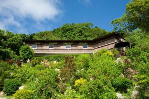 a building in the middle of a garden with trees at Kaiza in Nanjo