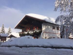 dom pokryty śniegiem z przodu w obiekcie Gästehaus Katharina w mieście Hochfilzen