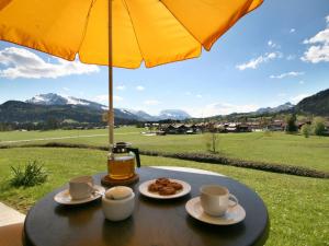 een tafel met bekers en borden eten en een paraplu bij Ferienwohnung Rosendahl in Reit im Winkl