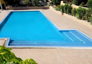 a large swimming pool with blue water in a yard at La Perla: Sea View and Pool (family apartment) in El Médano