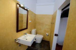 ein Badezimmer mit einem Waschbecken, einem WC und einem Spiegel in der Unterkunft Bastille in Galle