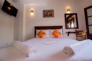ein Schlafzimmer mit einem großen weißen Bett mit orangefarbenen Kissen in der Unterkunft Bastille in Galle