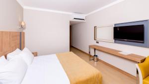 a hotel room with a bed and a flat screen tv at Julian Club Hotel in Marmaris