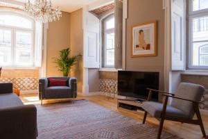 a living room with a television and two chairs at Alfama Baixa Spacious And Bright Apartment Blends the Historic and the Contemporary 2 Bedrs & 2 Bathrs AC 18th Century Building in Lisbon