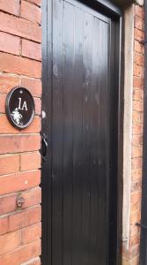 a black door on the side of a brick building at Cosy Apartment in Private Courtyard in Preston