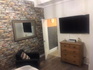 uma sala de estar com televisão numa parede de tijolos em Cosy Apartment in Private Courtyard em Preston