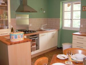una cucina con pareti verdi, armadi bianchi e tavolo di le Vitrier a Saint-Jean-de-Muzols