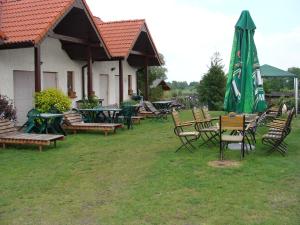 um grupo de mesas e cadeiras com um guarda-sol verde em Gospodarstwo Agroturystyczne Ania i Filip em Izabelin