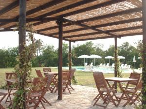 a group of tables and chairs under a wooden pergola at Agriturismo Le Docce in Castelfiorentino