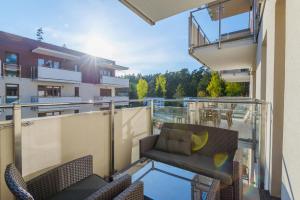 a balcony with a couch and chairs on a building at APARTAMENTY MIERZEJA - BALTIC PARK STEGNA, 33m2-57m2, 500 m od plaży, Bezpłatny Meleks in Stegna