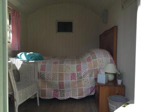 ein Schlafzimmer mit einem Bett mit einer Decke und einem Stuhl in der Unterkunft Cherryberry Lodges in Abergavenny