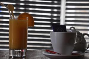ディナンにあるカフェ　ホテル　デュ　テアトルのオレンジジュース1杯、テーブルの上にカップ1杯
