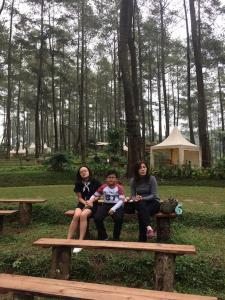 3 femmes assises sur un banc dans un parc dans l'établissement Apartemen Ciumbuleuit 2, à Bandung