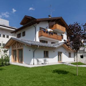 Un edificio blanco con dos mesas y sillas en un patio. en Appartamento Fuoco, en Andalo