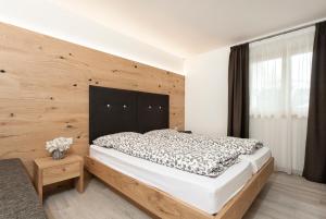 Un dormitorio con una cama grande con cabecero de madera. en Appartamento Fuoco, en Andalo