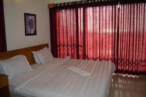 a bedroom with a white bed with red curtains at Resort Islandia in Cox's Bazar