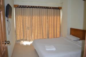 a bedroom with a bed and a window with curtains at Resort Islandia in Cox's Bazar
