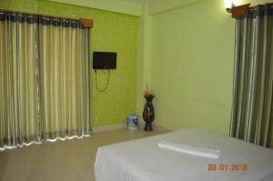 a bedroom with a bed and a tv on the wall at Resort Islandia in Cox's Bazar