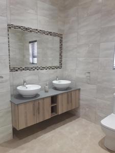 a bathroom with two sinks and a mirror at Cottage@Somerset in Somerset West