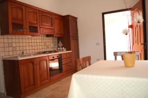 a kitchen with wooden cabinets and a table with a white table cloth at L'Agave in SantʼAntìoco