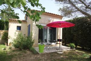 een rode parasol en een tafel en stoelen op een patio bij ENTRE AVIGNON et PONT DU GARD in Rochefort-du-Gard