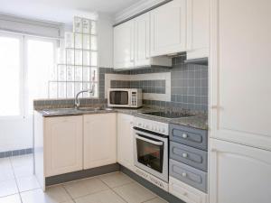 uma cozinha com armários brancos, um lavatório e um micro-ondas em Apartment Keops by Interhome em Casas Devesa