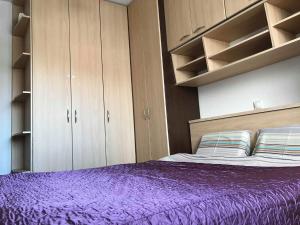 a bedroom with a purple bed and wooden cabinets at Redon's City Center Apartment in Prishtinë