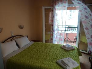 a bedroom with a green bed and a balcony at Maistralis House in Agios Gordios