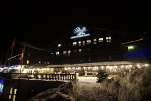 un bâtiment avec des lumières dans la neige la nuit dans l'établissement Champoussin Lodge, à Champoussin