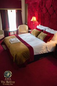 a bedroom with a large bed with a red headboard at The Belfray Country Inn in Derry Londonderry