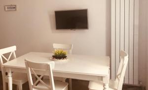 a white dining room table with white chairs and a tv at Zì Marì - Via Sirene in Polignano a Mare