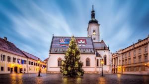 ein Weihnachtsbaum vor einem Gebäude mit einem Uhrturm in der Unterkunft Time Apartments Downtown in Zagreb