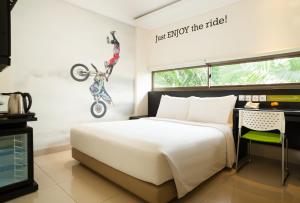 a bedroom with a bed with a motorcycle on the wall at Grandmas Plus Hotel Seminyak in Seminyak