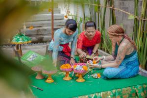 three women sitting around a table with a cake at Grandmas Plus Hotel Seminyak in Seminyak